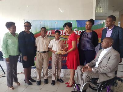 A student receives a stationery kit from Mrs Sharon Rowley, wife of Prime Minister, Dr Keith Rowley. Looking on are President of En ToTo Mrs JoAnne Harroo-Blackman and Permanent Secretary Jacinta Bailey-Sobers (1st and 2nd from left) and other well-wishers present at the Stationery Kit Distribution on March 26th.